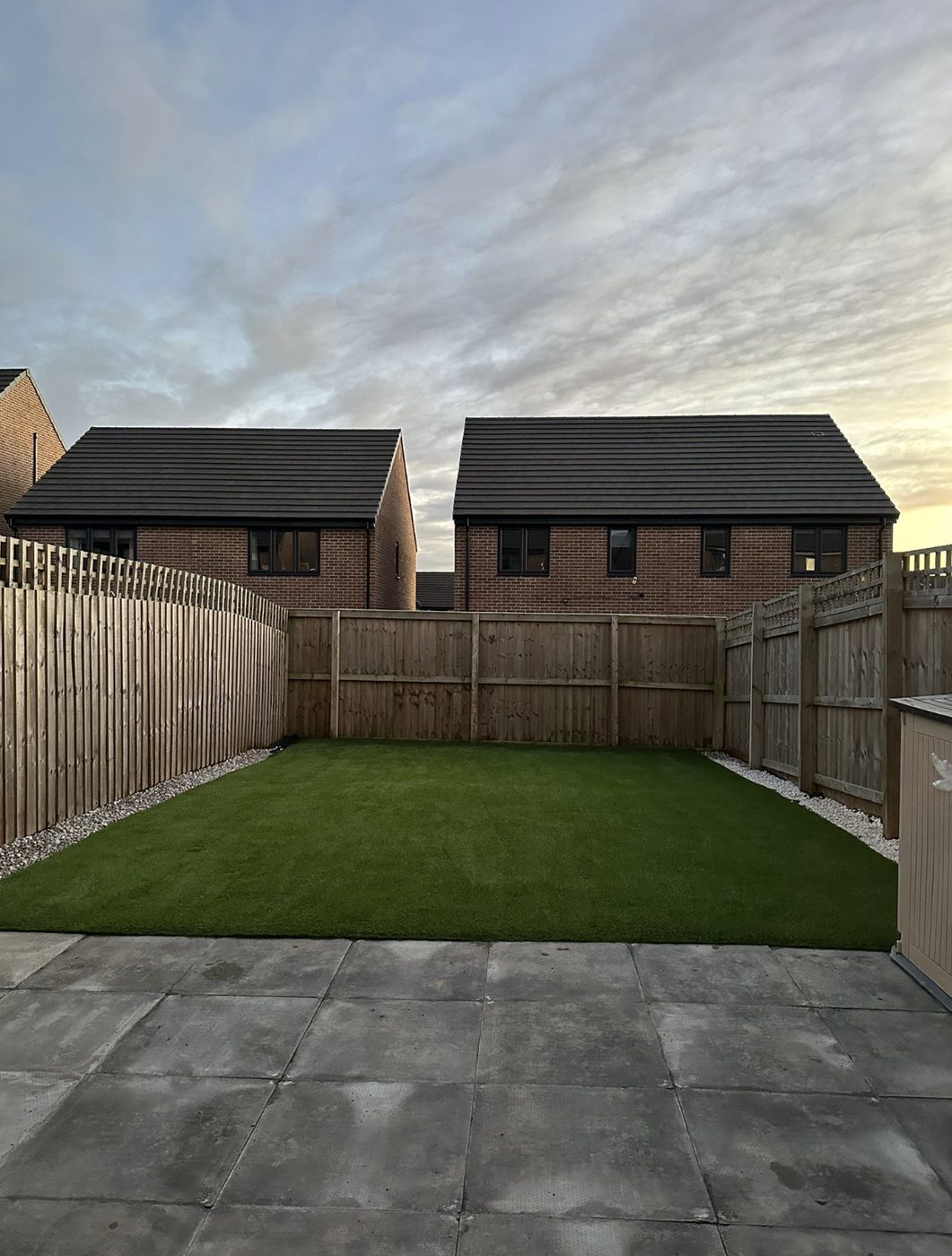 Artificial grass lawn with gravel edges in a new build garden