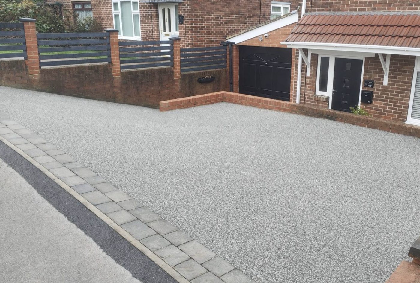 Grey resin driveway edged with stone setts