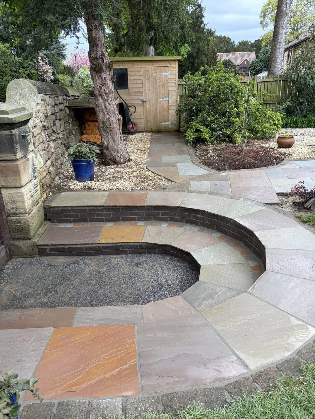 Curved Indian sandstone steps with brick risers leading to a shed