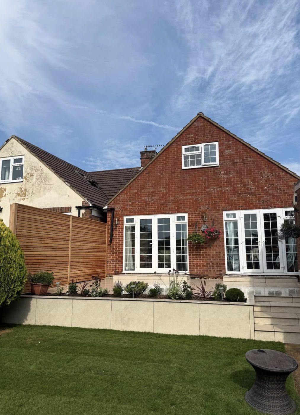 Slatted timber screen beside a house with a rendered raised planter and patio